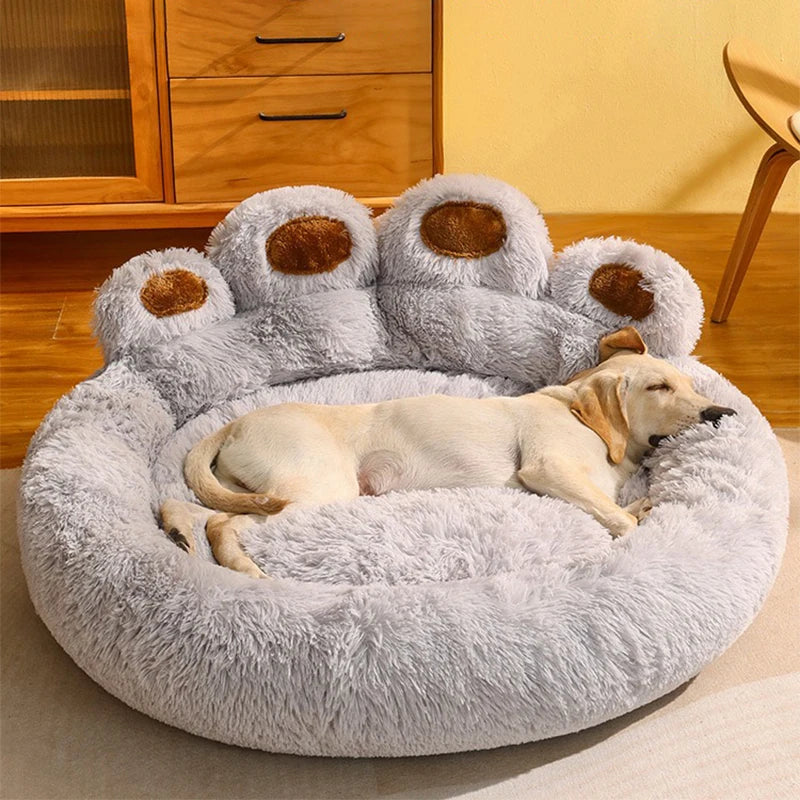 Dog lying on a fluffy paw-shaped pet bed in a room with wooden furniture.