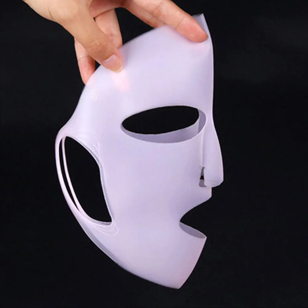 White mask with black eye sockets held by a hand against a black background