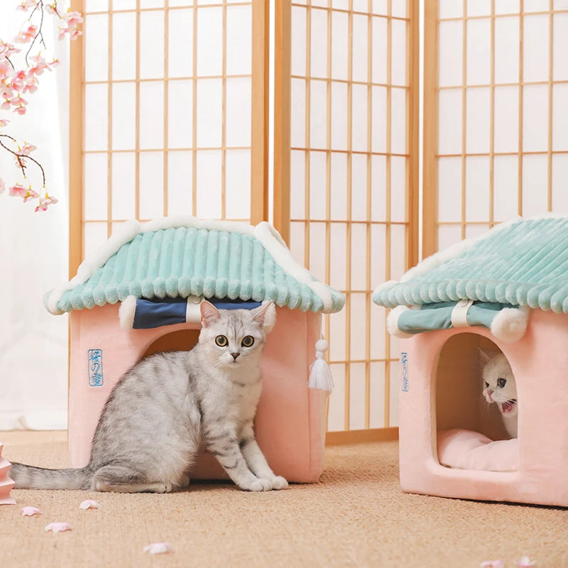 Two small pet houses with cats inside against a light wooden panel background