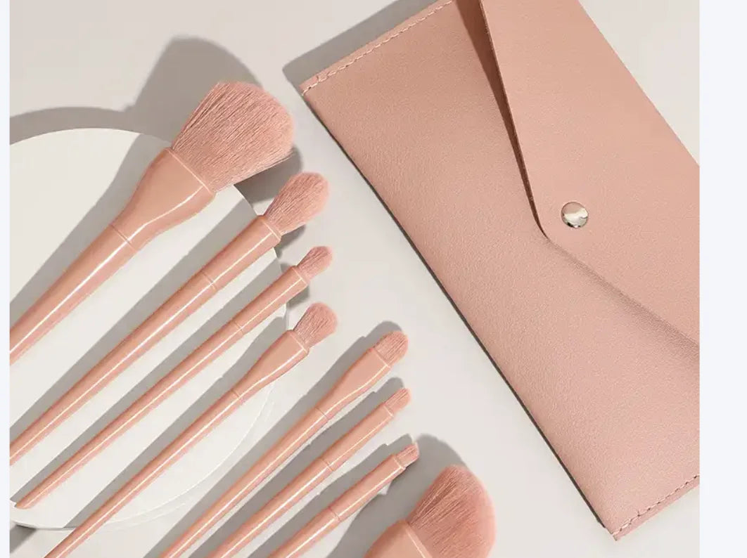 Set of rose gold makeup brushes with a matching case on a light background