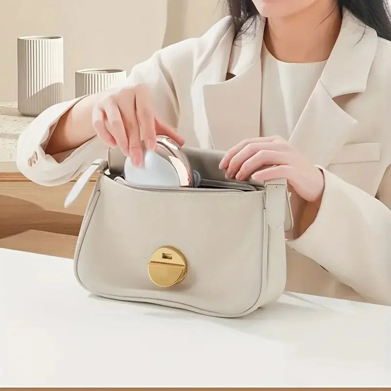 Person opening a beige handbag with a gold clasp on a light background