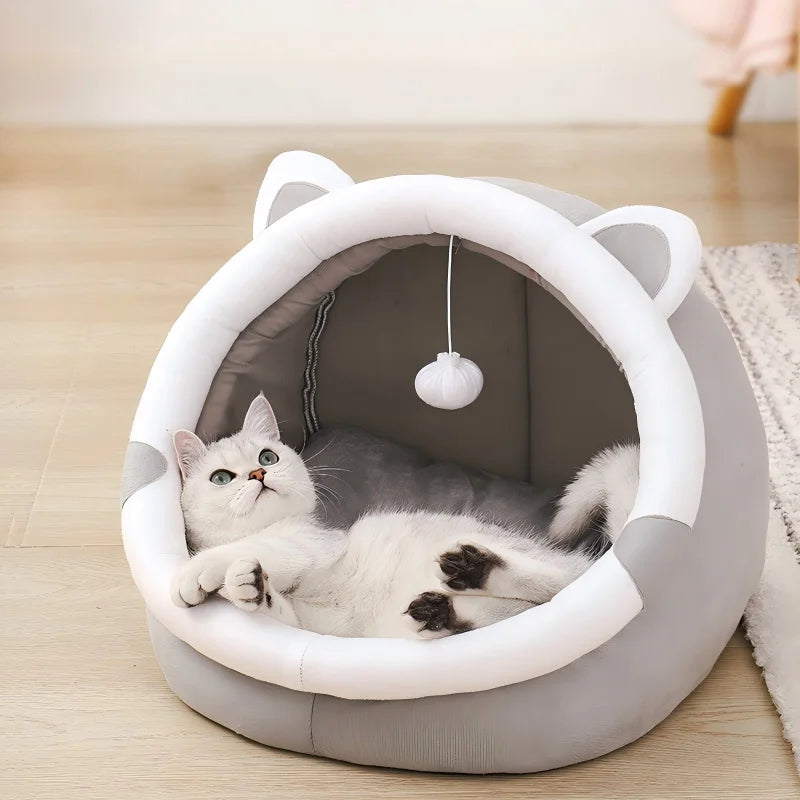 Cat lying in a gray pet bed with cat ears on a wooden floor.