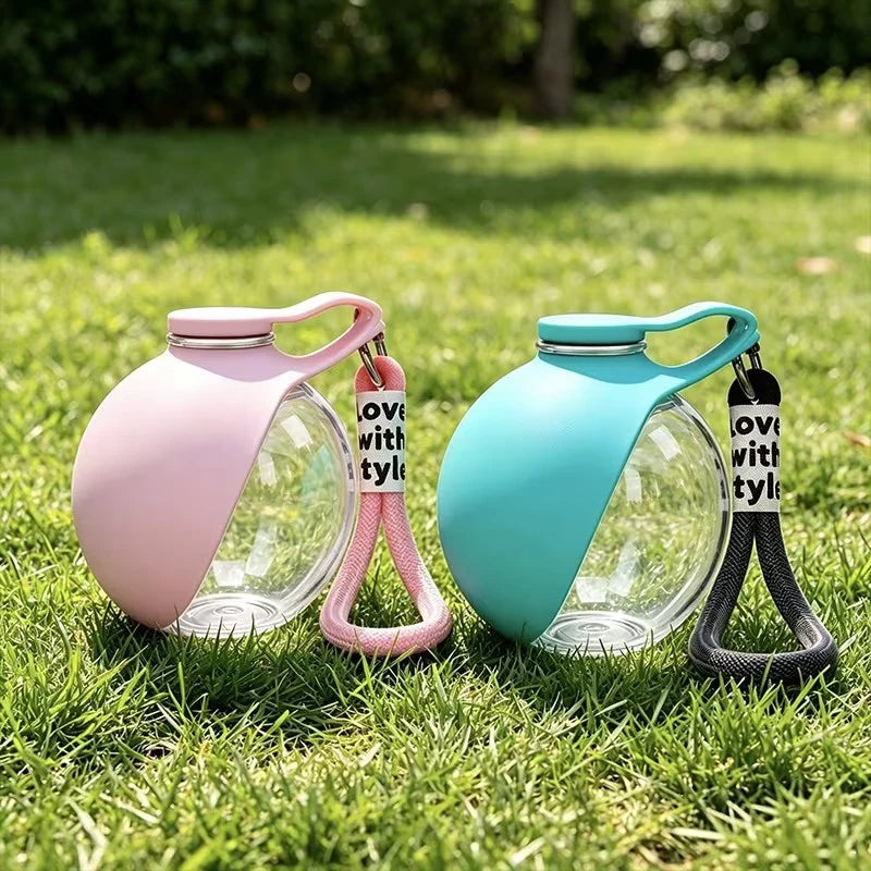 Pink and blue pet water bottles with handles on grass