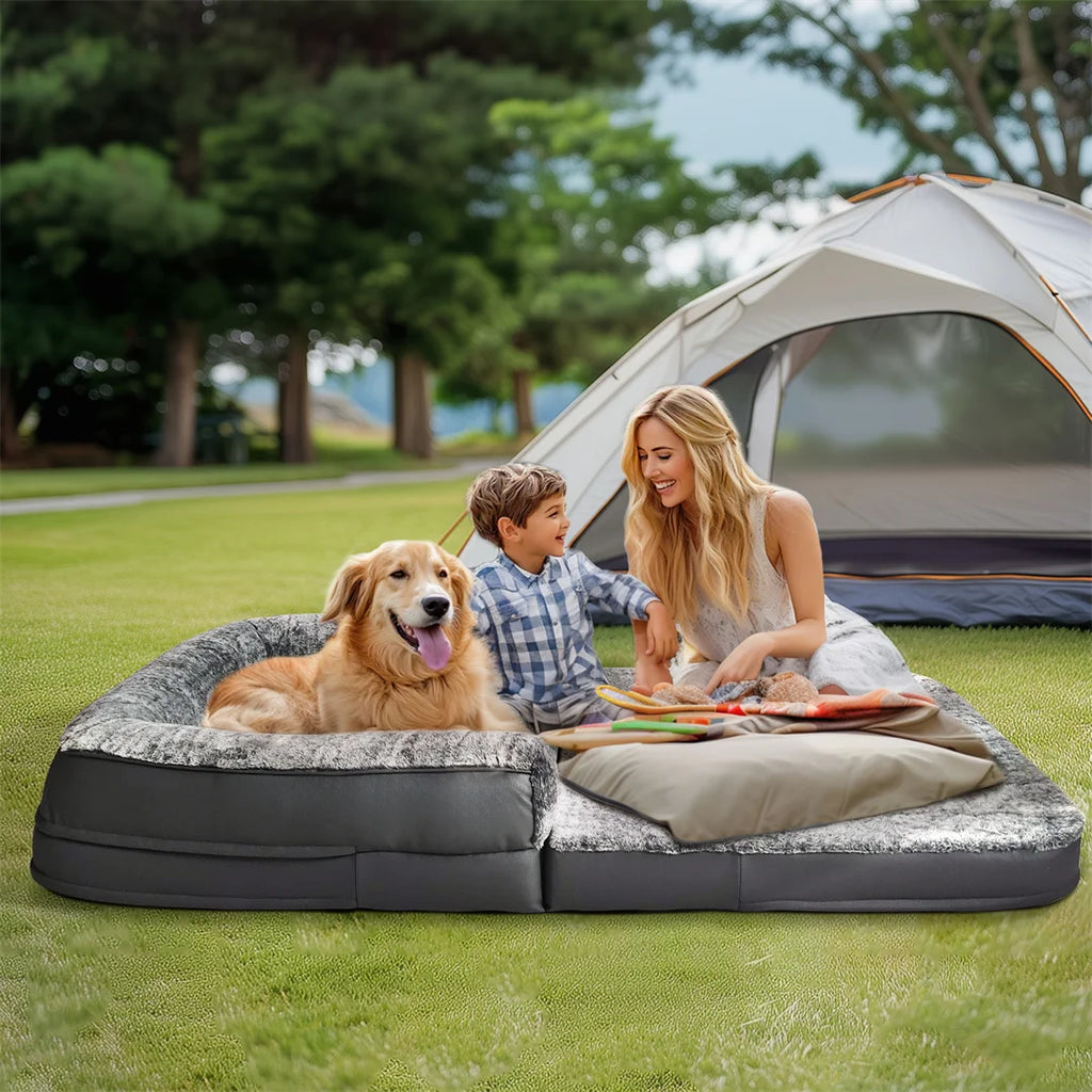 Woman and child with a dog on a large inflatable camping mattress in front of a tent.