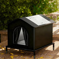 Black pet house on a wooden deck with greenery in the background
