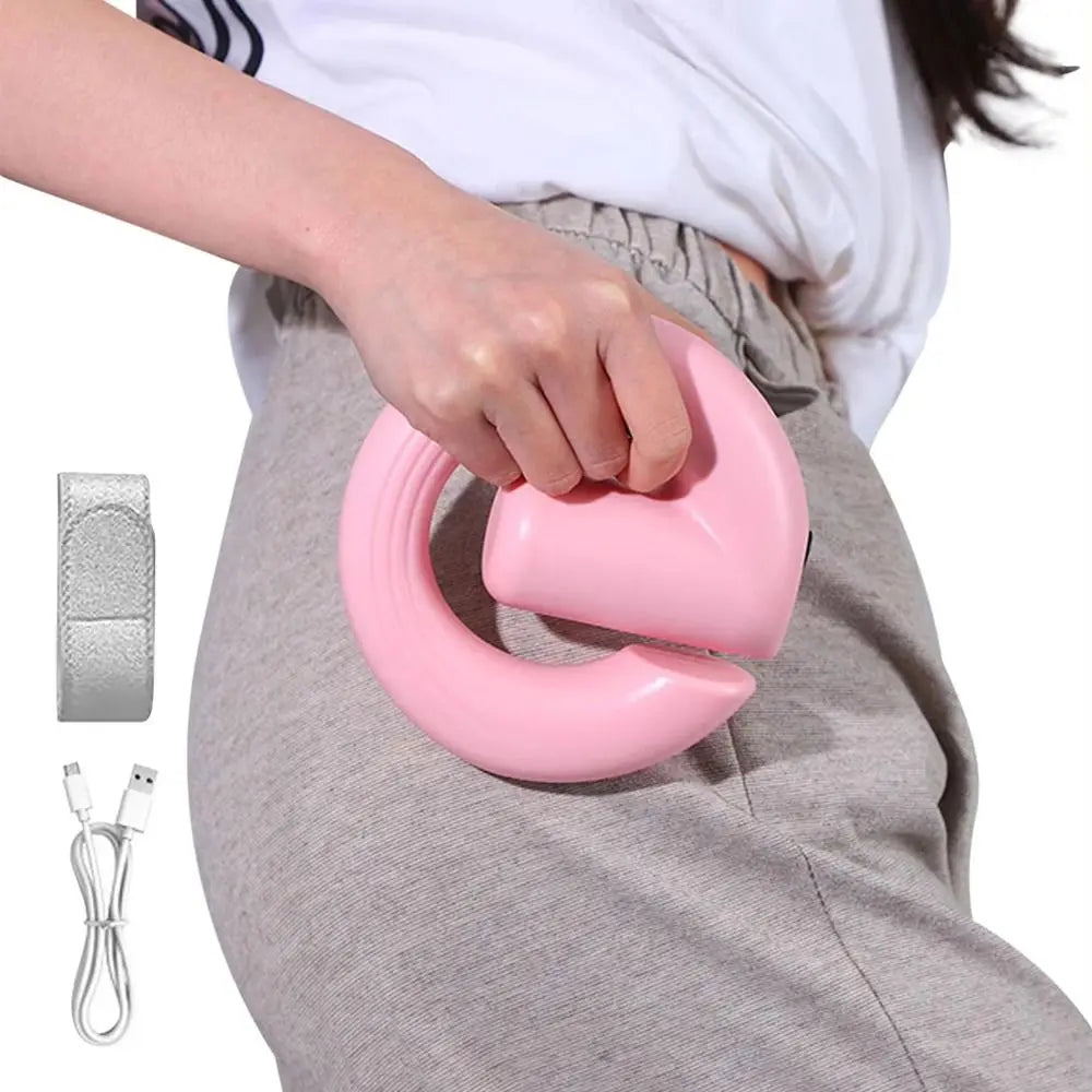 A person wearing gray sweatpants and a white top demonstrates a pink pelvic floor trainer on their lower torso. The image includes a small inset showing a silver carrying strap and a white USB charging cable against a white background.