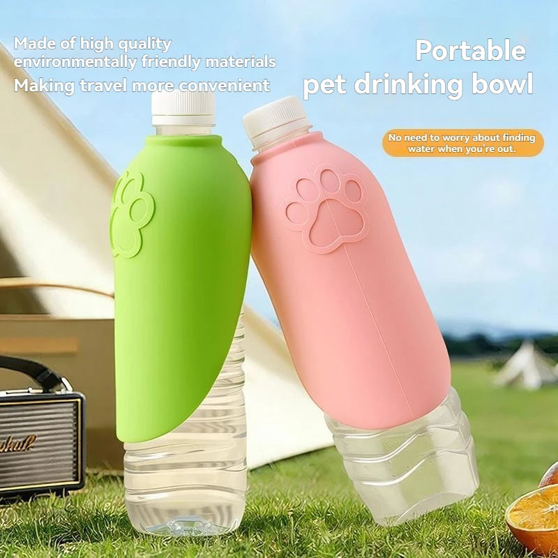 Two portable pet drinking bowls in green and pink, designed to fit over plastic water bottles, shown on a grassy lawn with a tent and outdoor background.