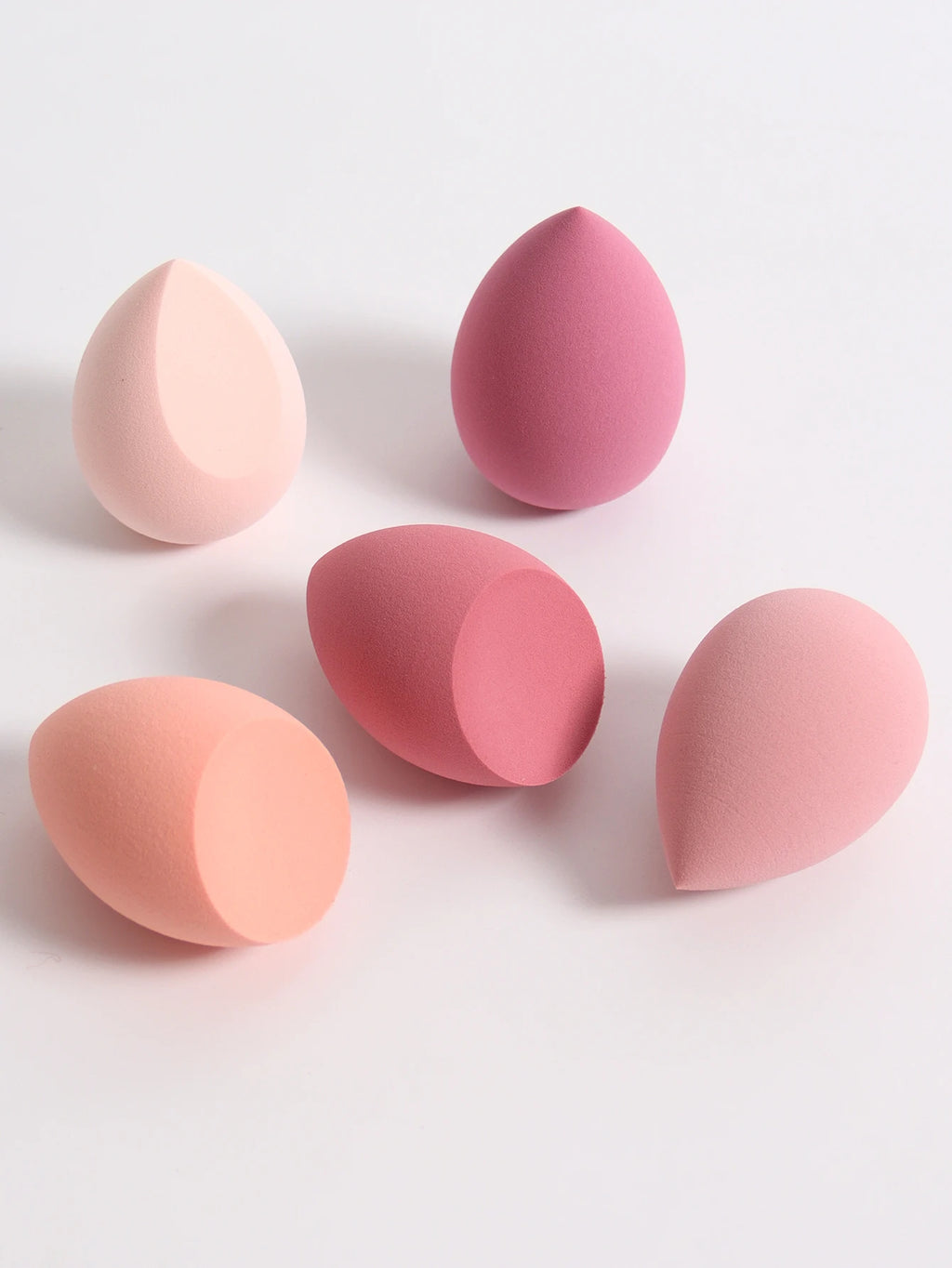 Set of pink and peach-colored makeup sponges on a light gray background