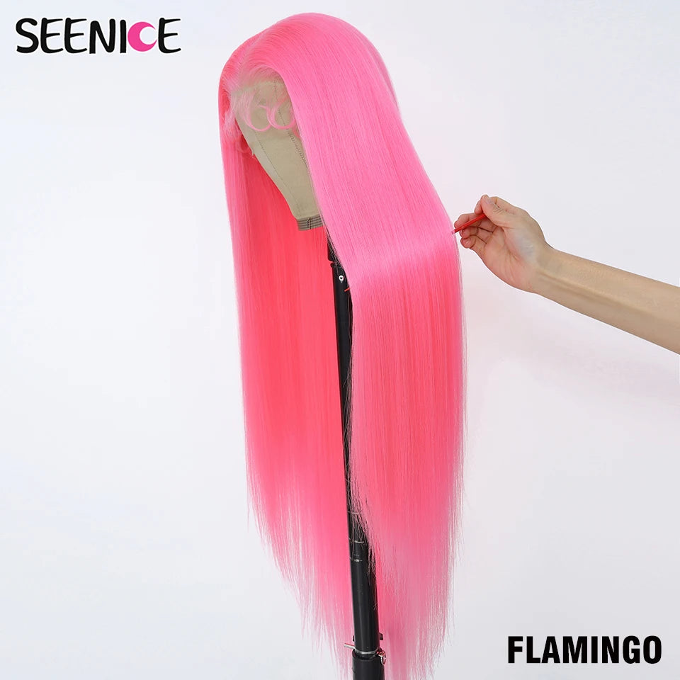 A bright pink straight wig displayed on a mannequin stand against a white background, with a hand holding the side of the hair to show its texture and length. The brand name 'SEENICE' is in the top left corner, and 'FLAMINGO' is in the bottom right.