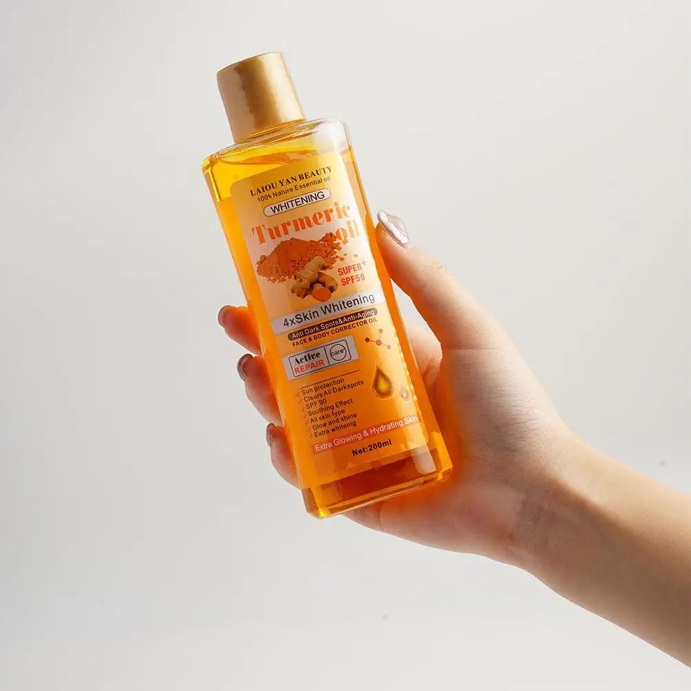 Hand holding a bottle of Lady Muck Turmeric Whitening Skin Whitening Oil against a light background