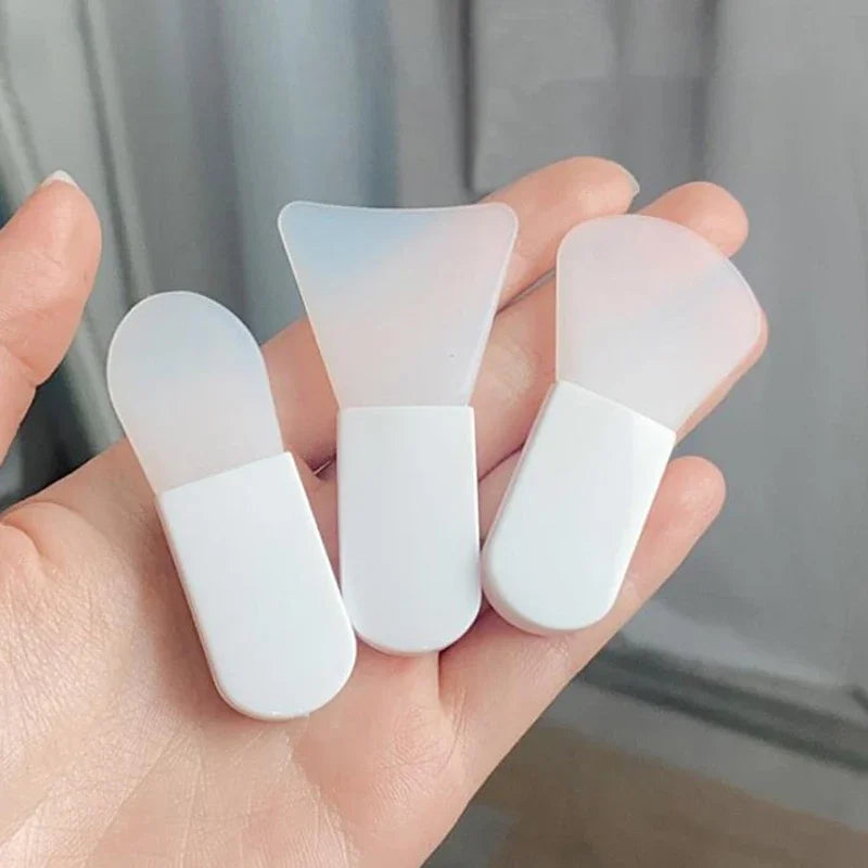 Three white silicone face masks held in a hand against a neutral background
