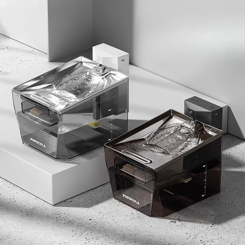 Two portable ice melts or melts in transparent containers with metallic silver and dark brown translucent lids, displayed on white geometric blocks against a gray concrete background. The brand name 'PONCOLA' is visible on the front of both containers.