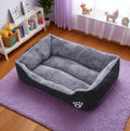 Gray pet bed on a purple rug in a room with a shelf and decorative items.