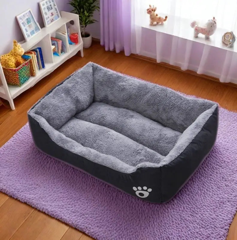 Gray pet bed on a purple rug in a room with a shelf and decorative items.