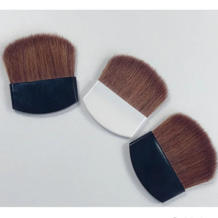 Three makeup brushes with brown bristles and black or white handles on a light gray background.
