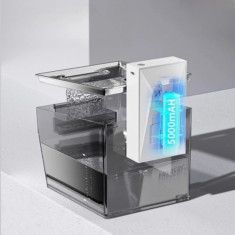 A modern countertop water filter pitcher with a clear acrylic base, a dark gray water reservoir, a stainless steel strainer basket, and a white cartridge housing a glowing blue LED display showing '5000mAh'.