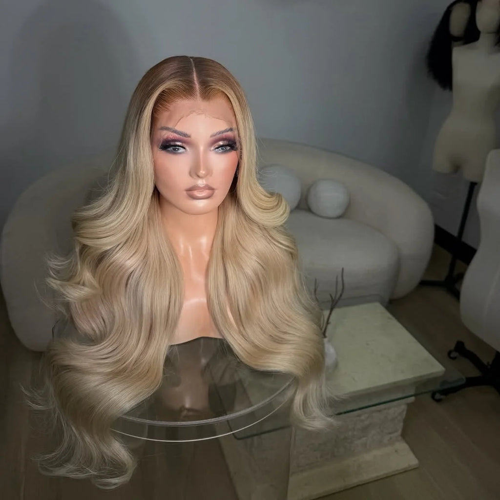Long, wavy blonde wig displayed on a mannequin bust in an indoor room setting with a sofa and table in the background.