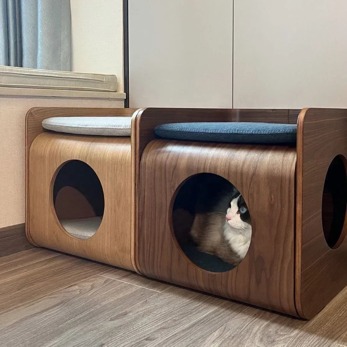 Wooden pet house with a cat peeking out on a wooden floor.