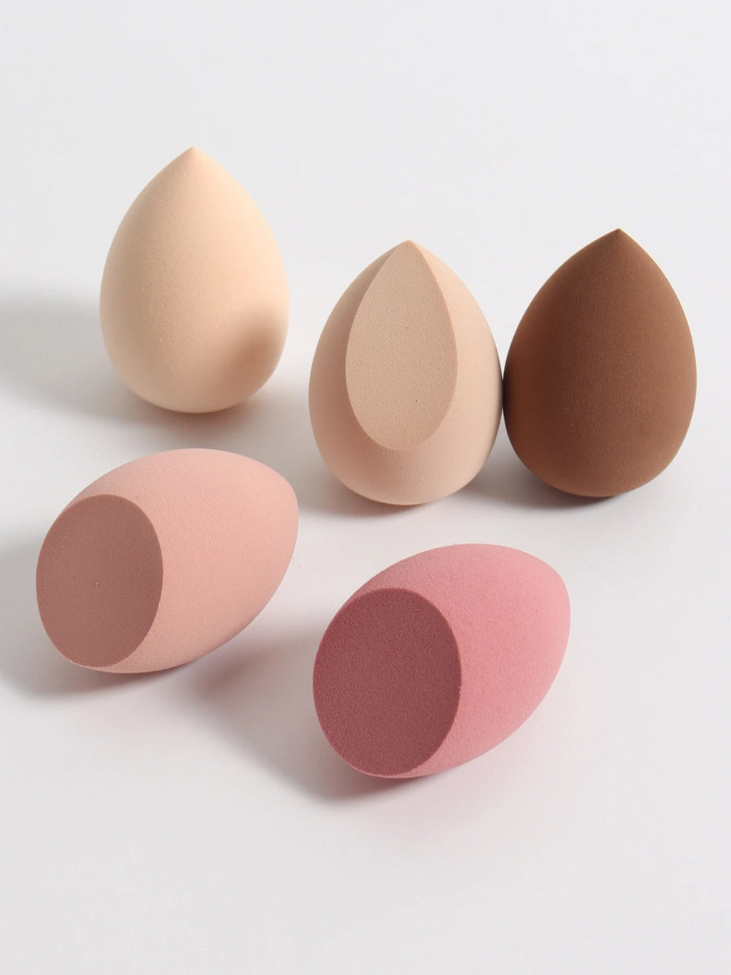 Set of five makeup sponges in various shades on a light gray background