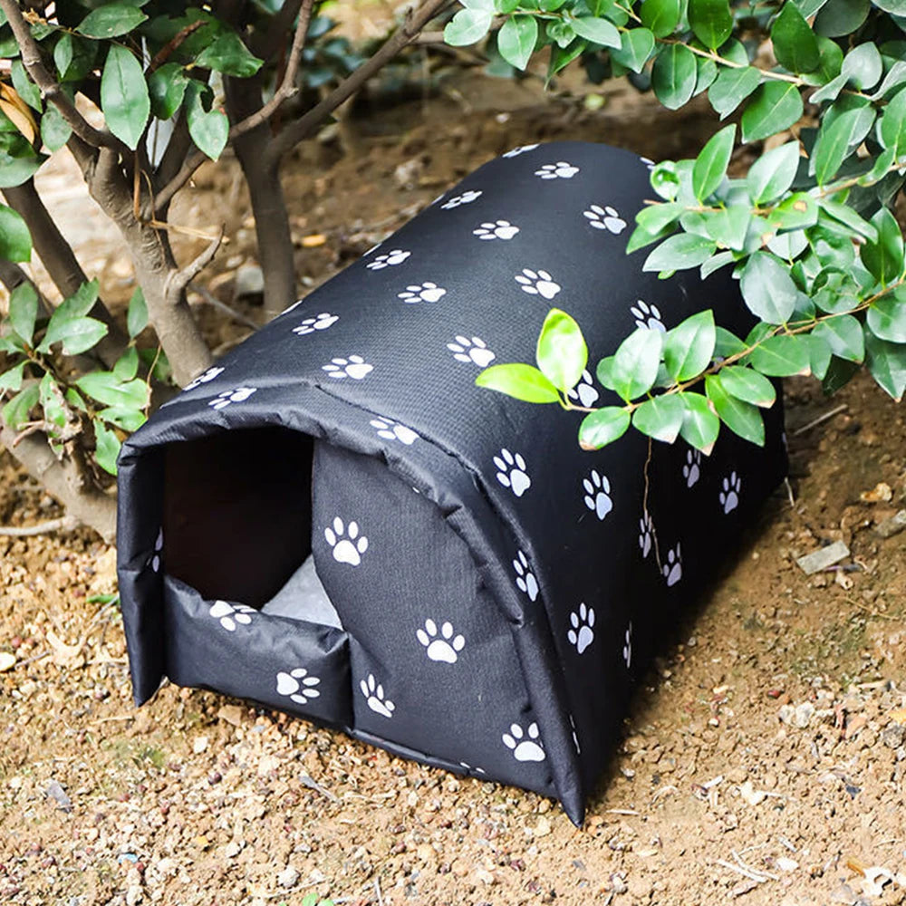 Black pet bed with white paw prints on a garden path