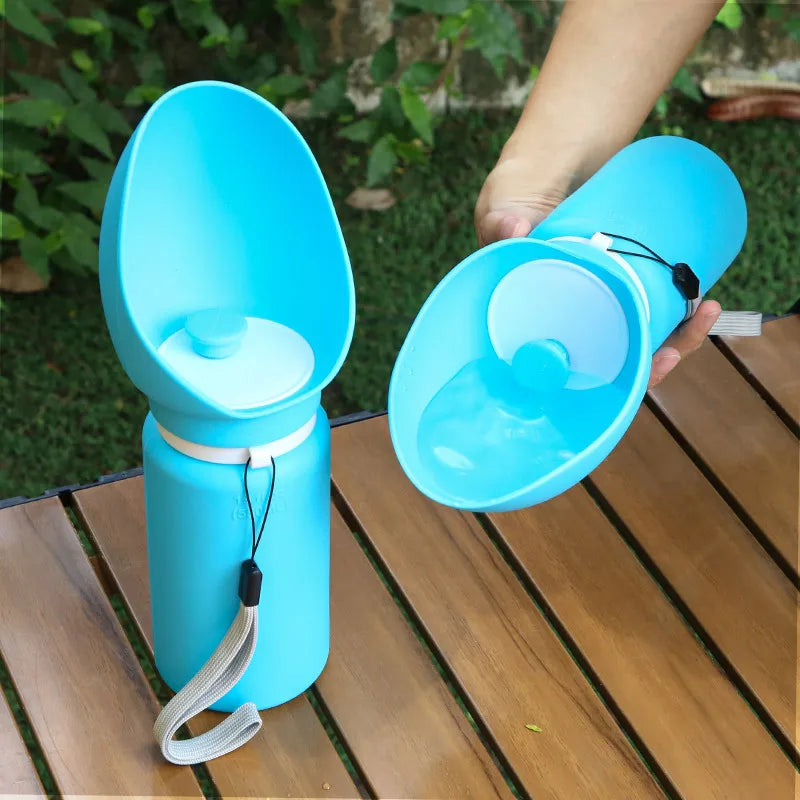 Blue portable pet water bottle held by a person on a wooden surface with greenery in the background
