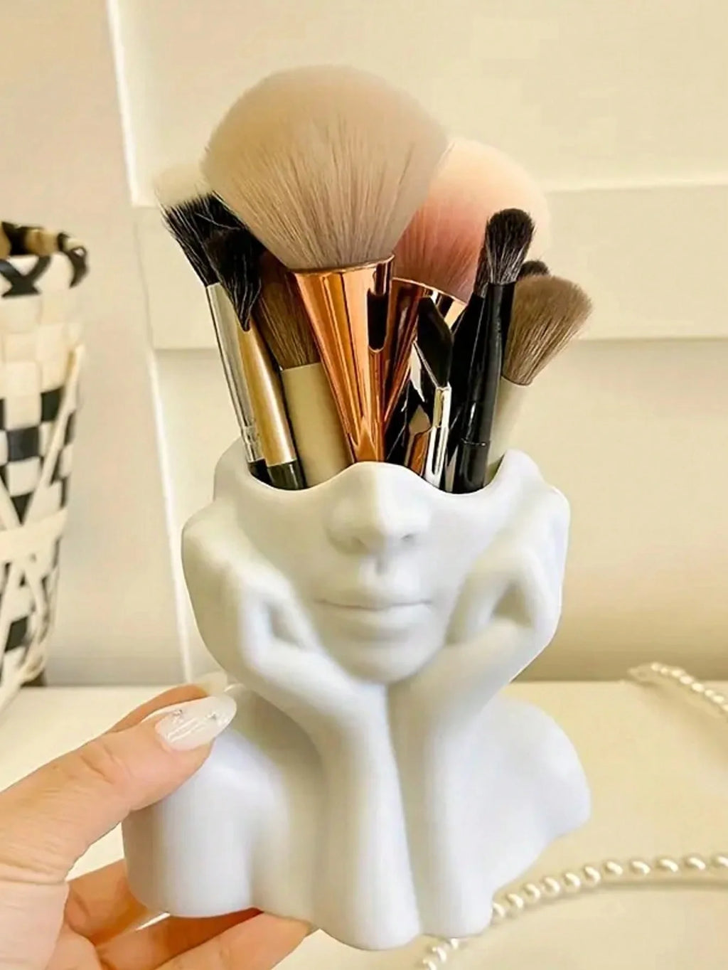 White ceramic holder with makeup brushes on a blurred background