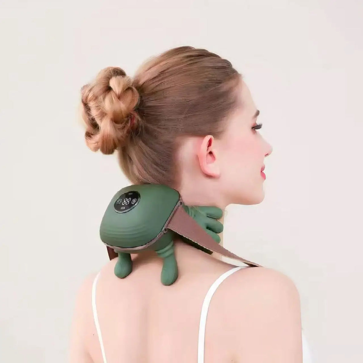 Person using a green neck and shoulder massager on a plain background