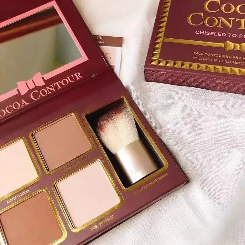 Makeup contour kit with shades and a brush in an open box on a white fabric background