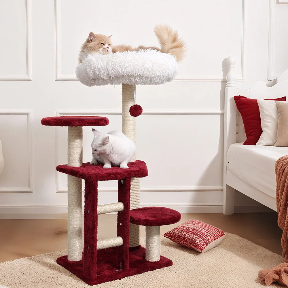 Cat tree with two cats in a room with a bed and pillows.