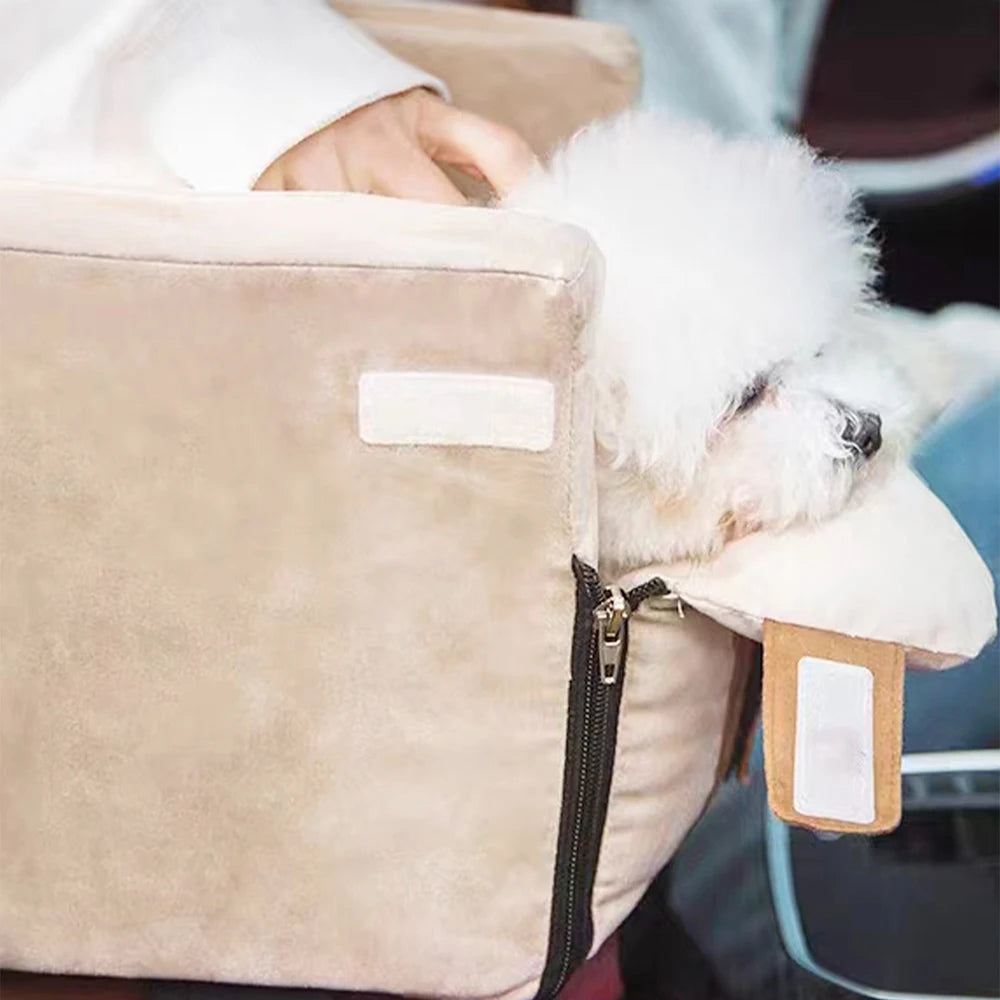 Small white dog peeking out from a beige pet carrier with a person holding it.
