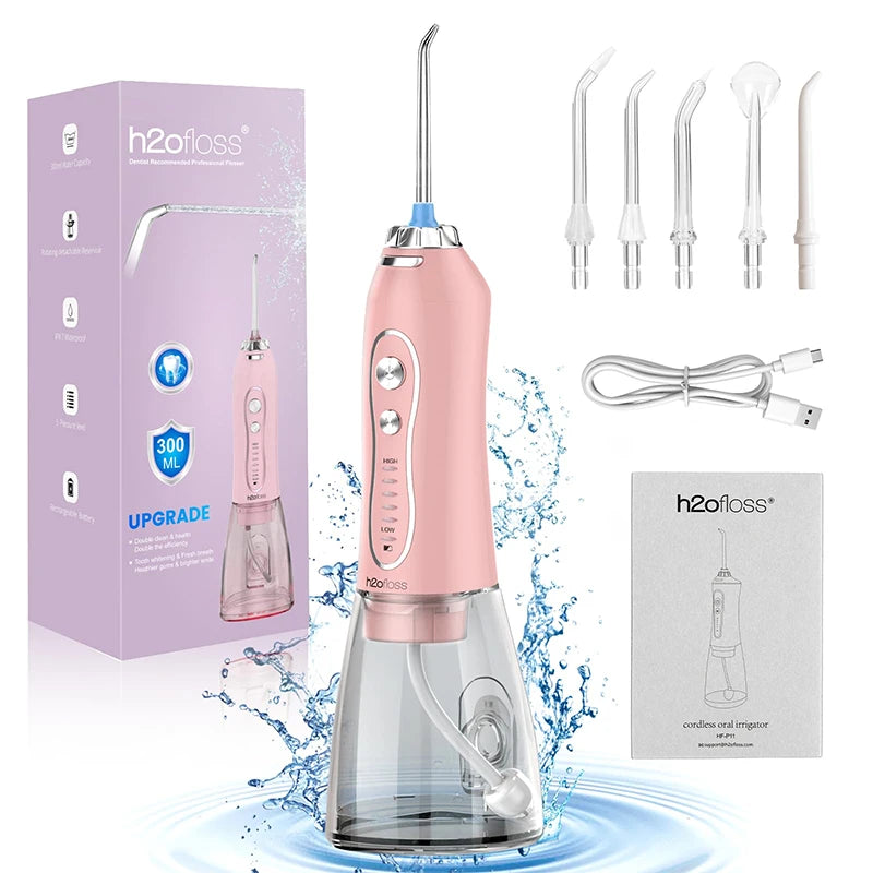 Pink water flosser with packaging, nozzles, and charging cable on a white background