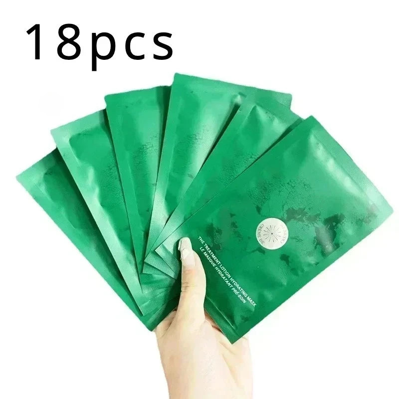 A hand holding a fan of eight green facial mask packets, with a black text overlay reading '18pcs' at the top left, on a plain white background.