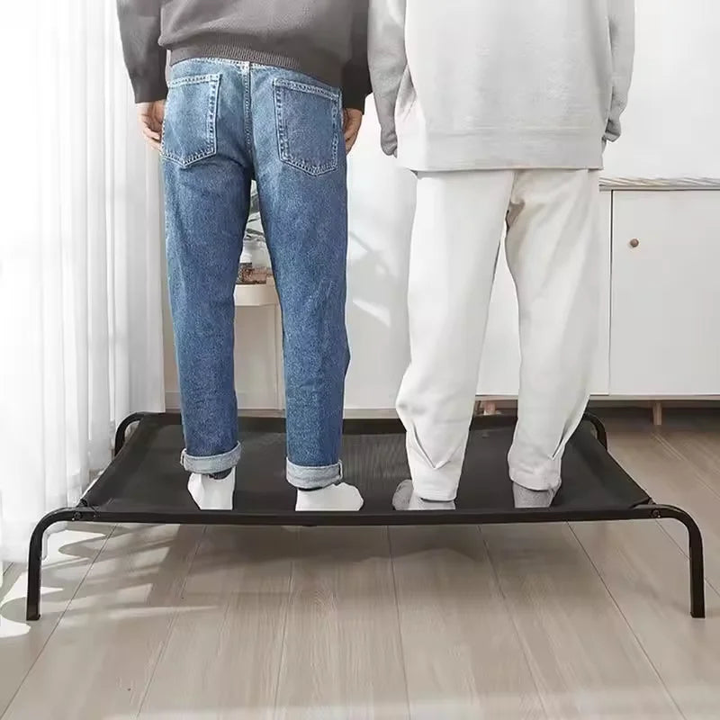Two people standing on a black platform in a room with white walls and wooden flooring.