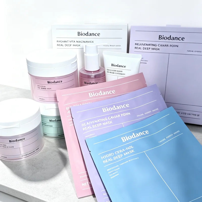 Biodance skincare set featuring multiple masks and serums in pastel pink, lavender, and blue packaging, arranged on a light marble surface with a white background.