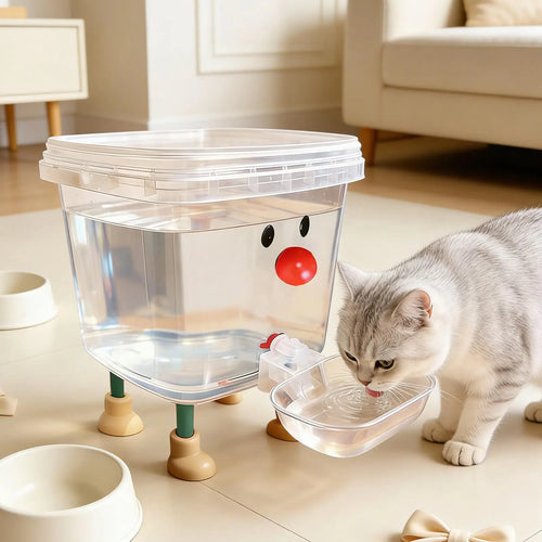 Cat drinking water from a transparent water dispenser with a red nose on a light-colored floor.