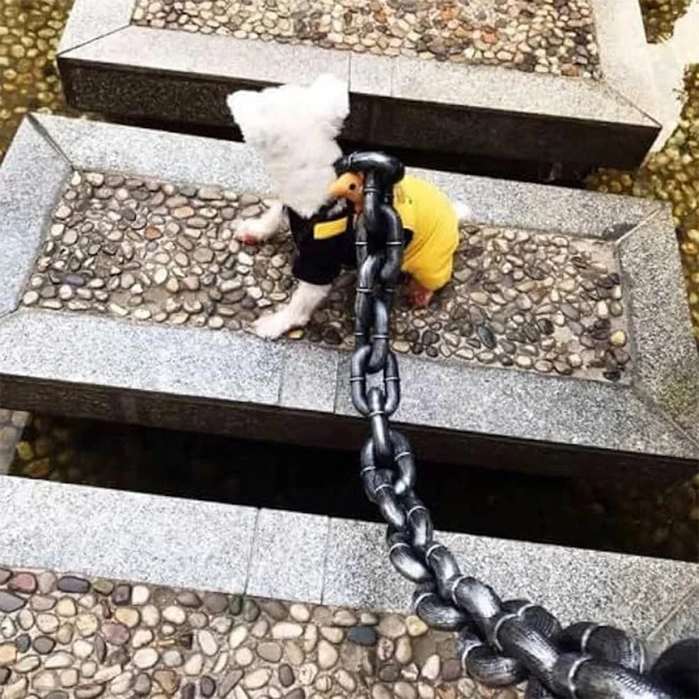 Small dog on a chain leash with a duck toy, standing on stone steps.