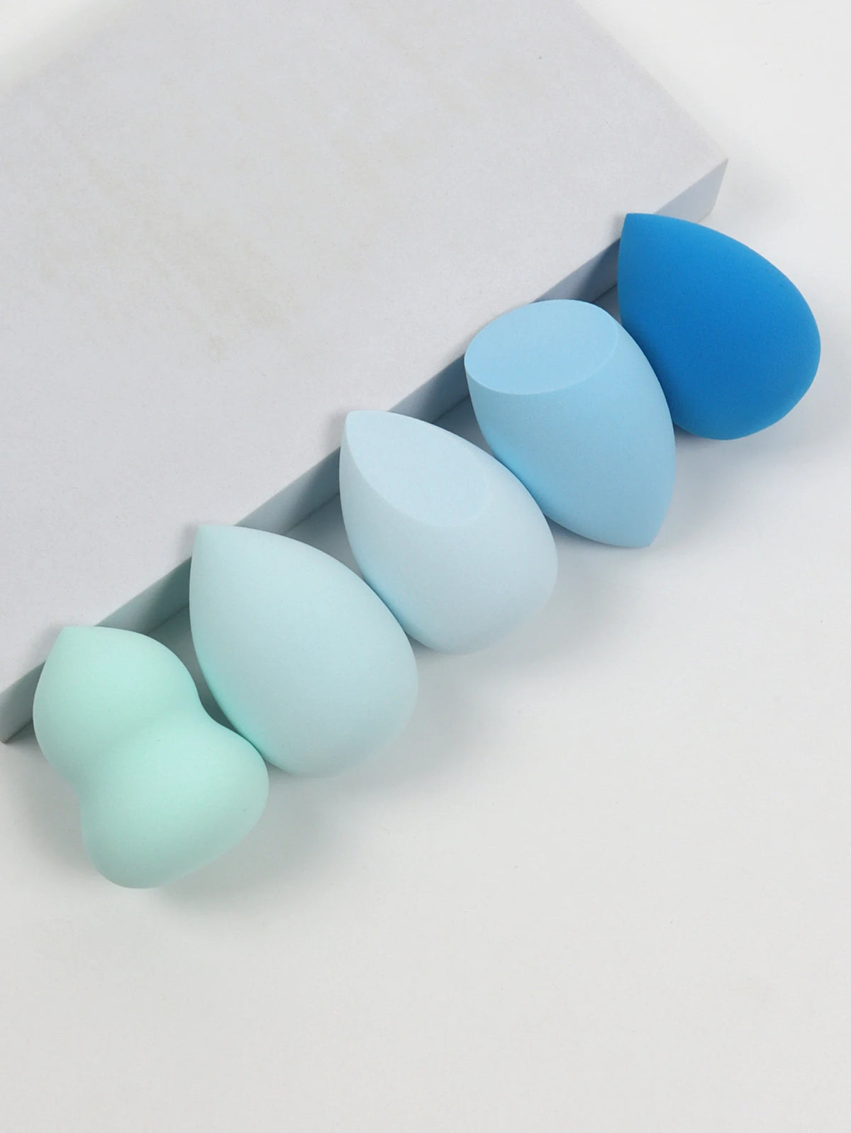 Set of blue and green makeup sponges on a white background