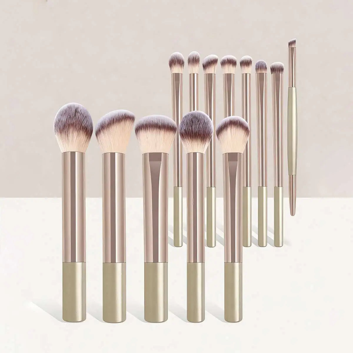 Set of makeup brushes with gold and silver handles on a light background