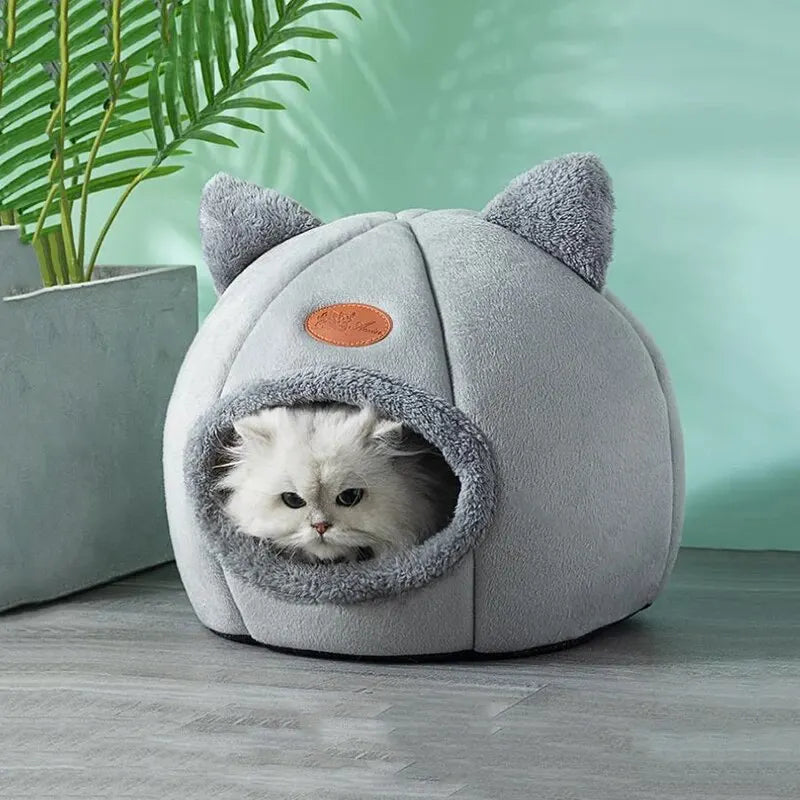 Gray pet bed shaped like a cat with a white cat inside, against a light green background.