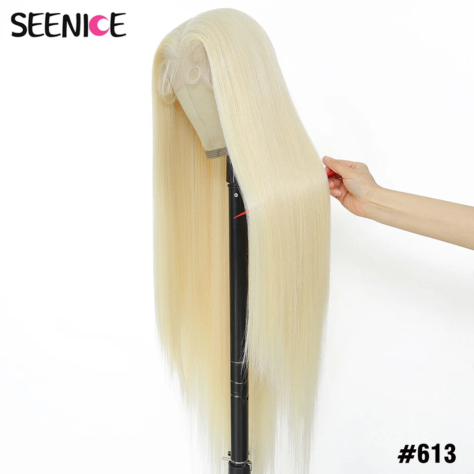 A long, straight synthetic wig in shade #613 blonde, displayed on a stand with a hand holding out a section to show its texture and volume. The brand 'SEENICE' is visible in the top left corner.