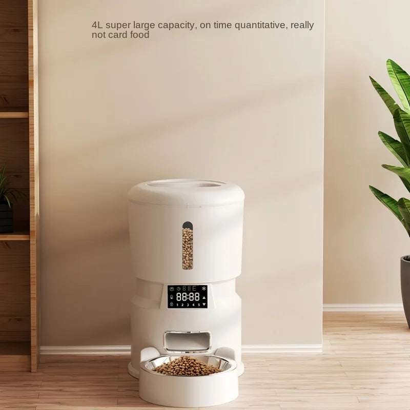 White pet food dispenser with digital display on a wooden floor, plant in the background