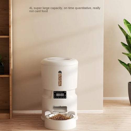 White pet food dispenser with digital display on a wooden floor, plant in the background