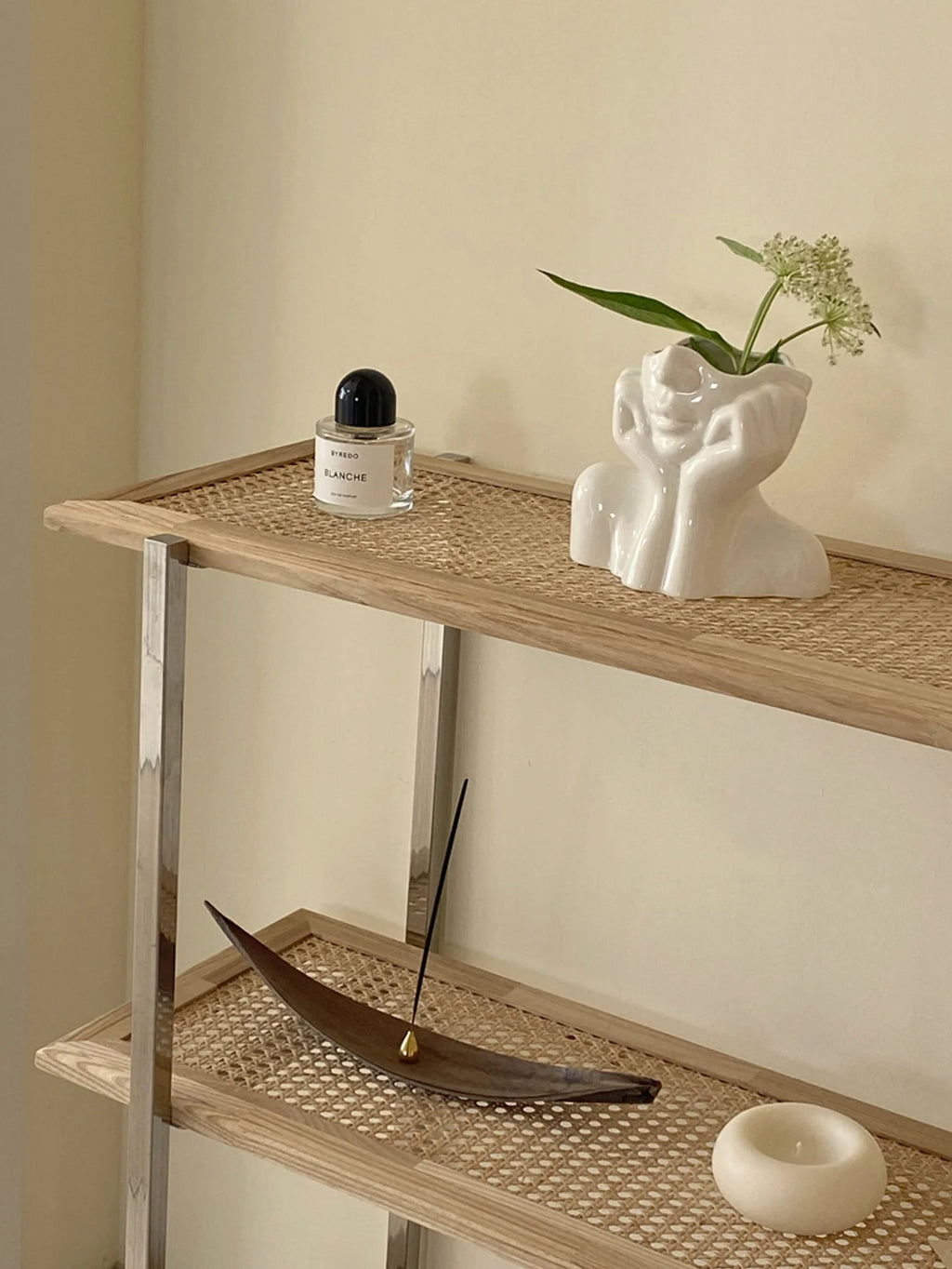 Wicker shelf with decorative items including a bottle, vase, and incense stick.