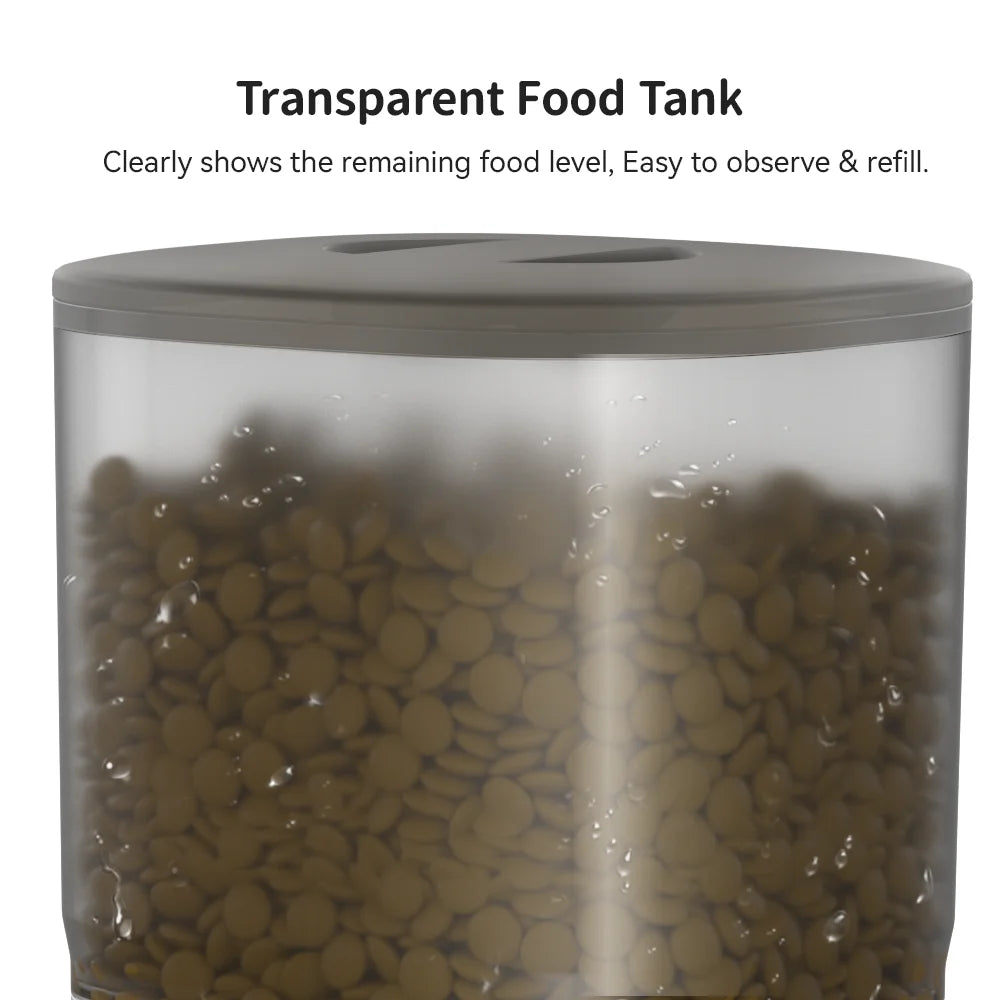 A clear cylindrical food storage tank with a dark gray lid, filled with brown kibble or pet food, with text above reading 'Transparent Food Tank' and 'Clearly shows the remaining food level, Easy to observe & refill.'.