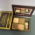 Cocoa contour makeup palette with brush and packaging on a gray surface