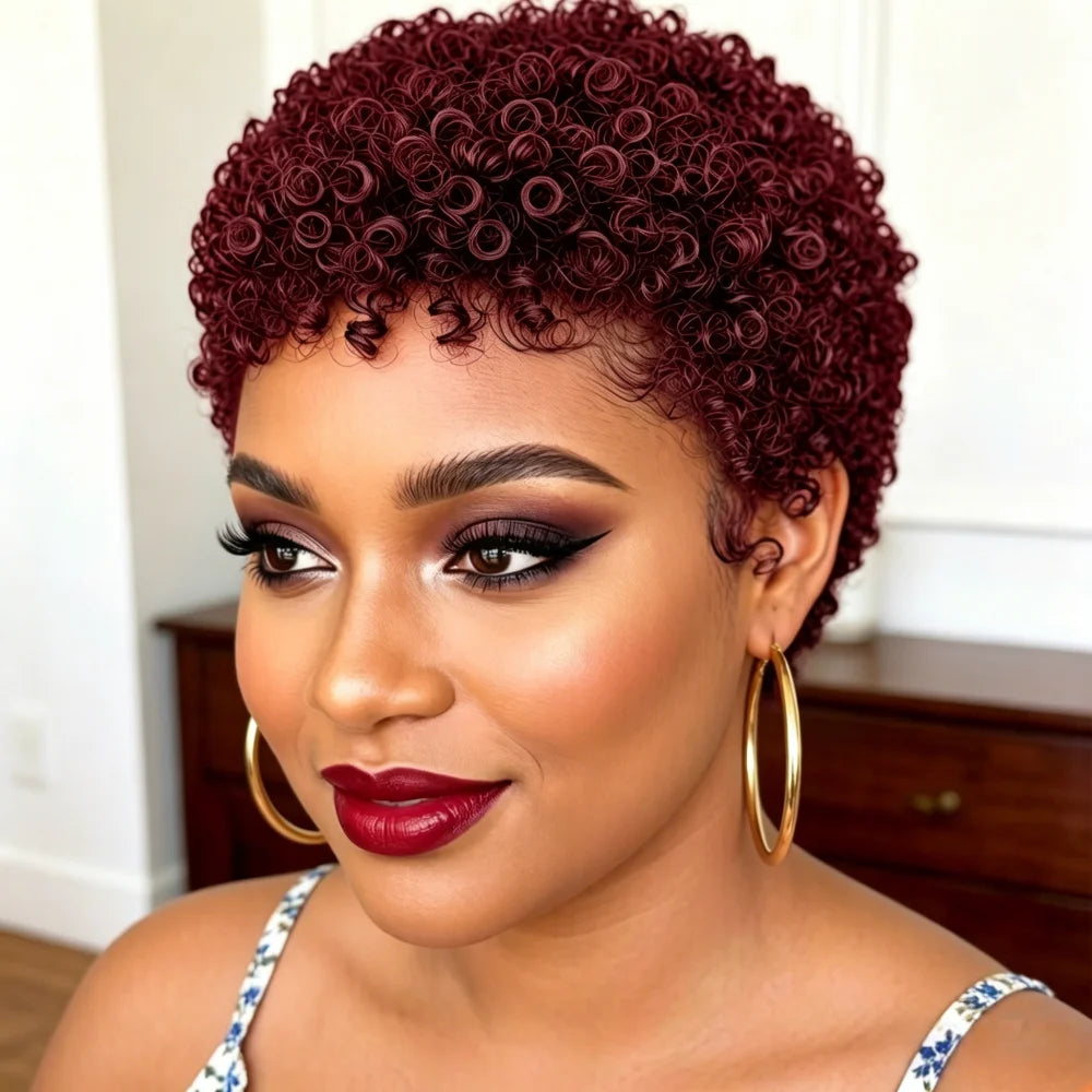 A close-up portrait of a woman with a short, tightly curled wig in deep burgundy. The wig is styled on a model with dramatic makeup, including black winged eyeliner, red lipstick, and gold hoop earrings, in an indoor setting.