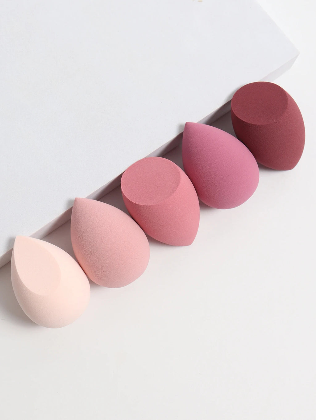 Set of pink and red makeup sponges on a white background