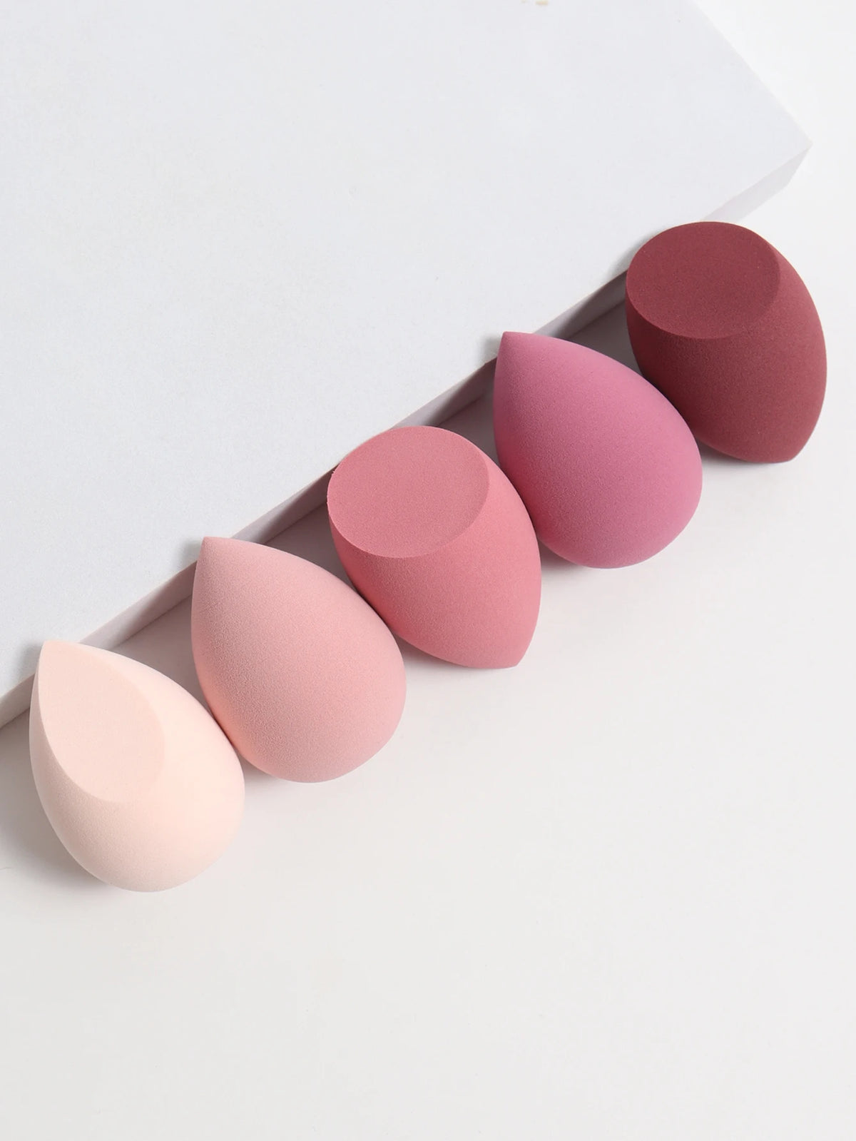 Set of pink and red makeup sponges on a white background