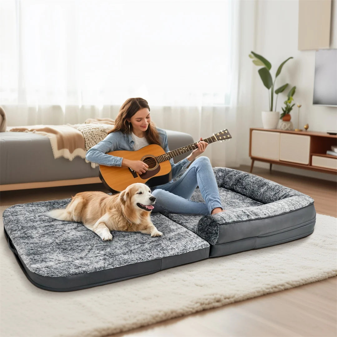 Woman playing guitar with a dog on a large pet bed in a living room.