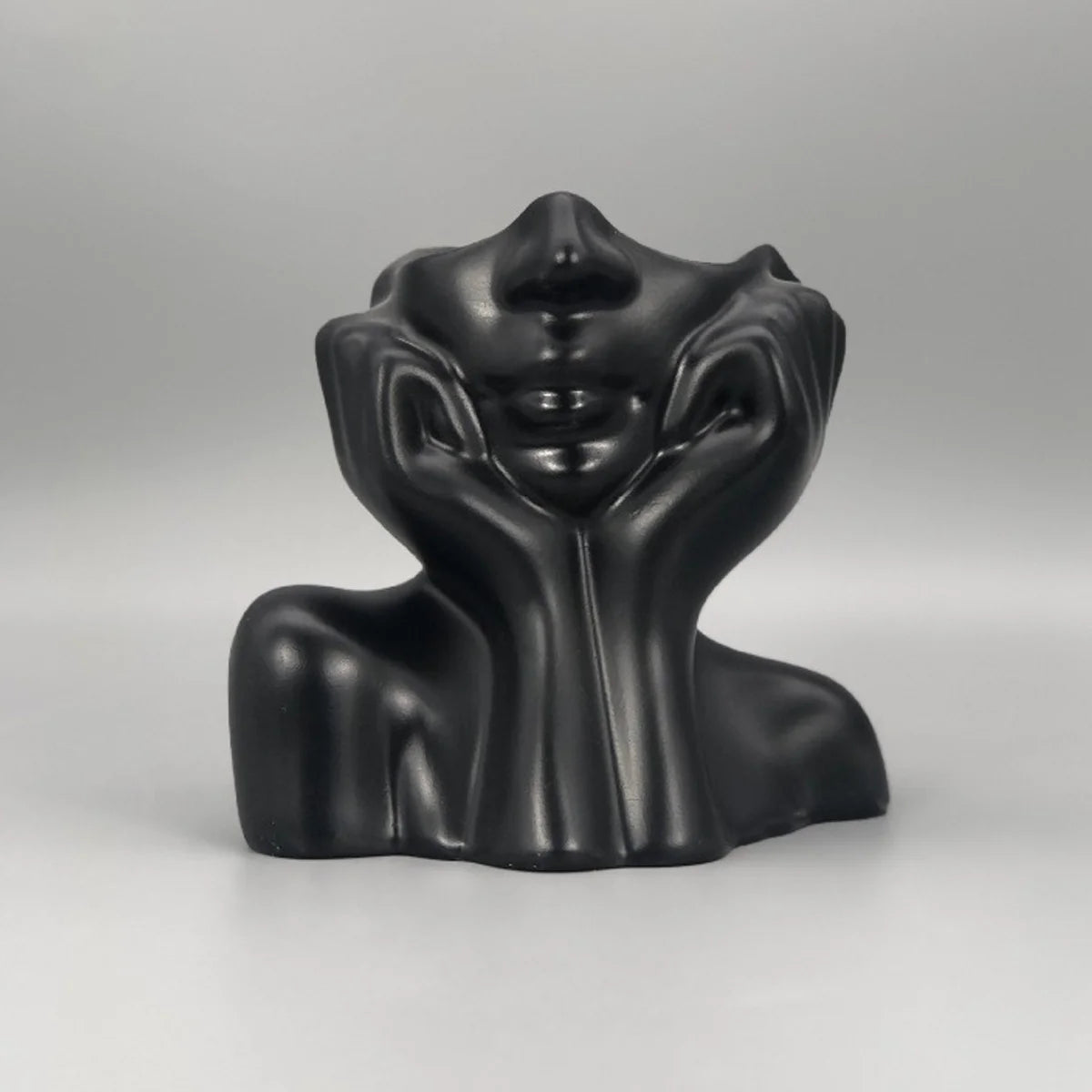Black abstract sculpture of a face on a gray background